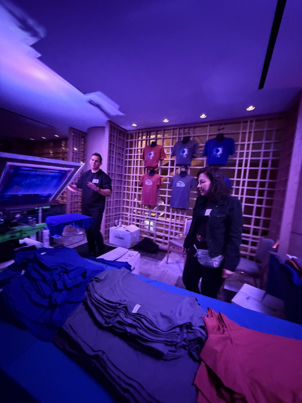 Evening merch table staged with product and lighting inside a booth